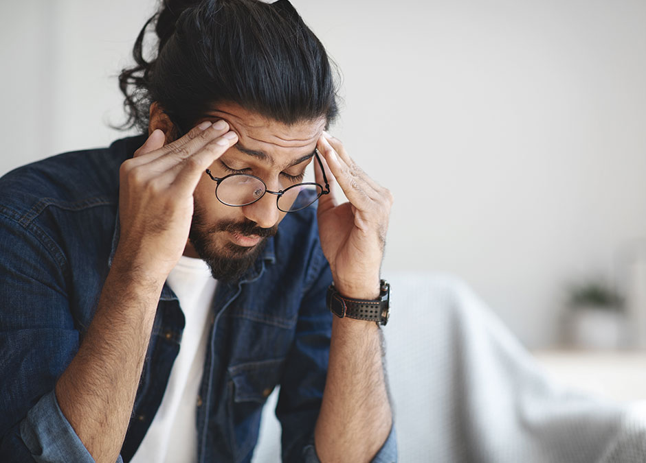 Young indian guy freelancer suffering from headache